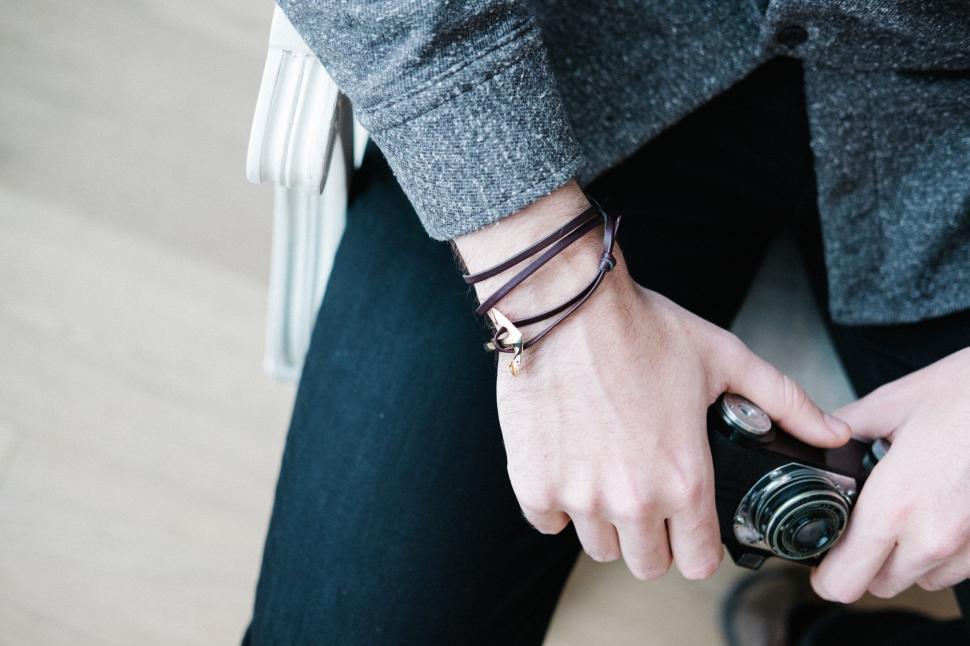 Free Image of Man holding camera with a stylish bracelet 