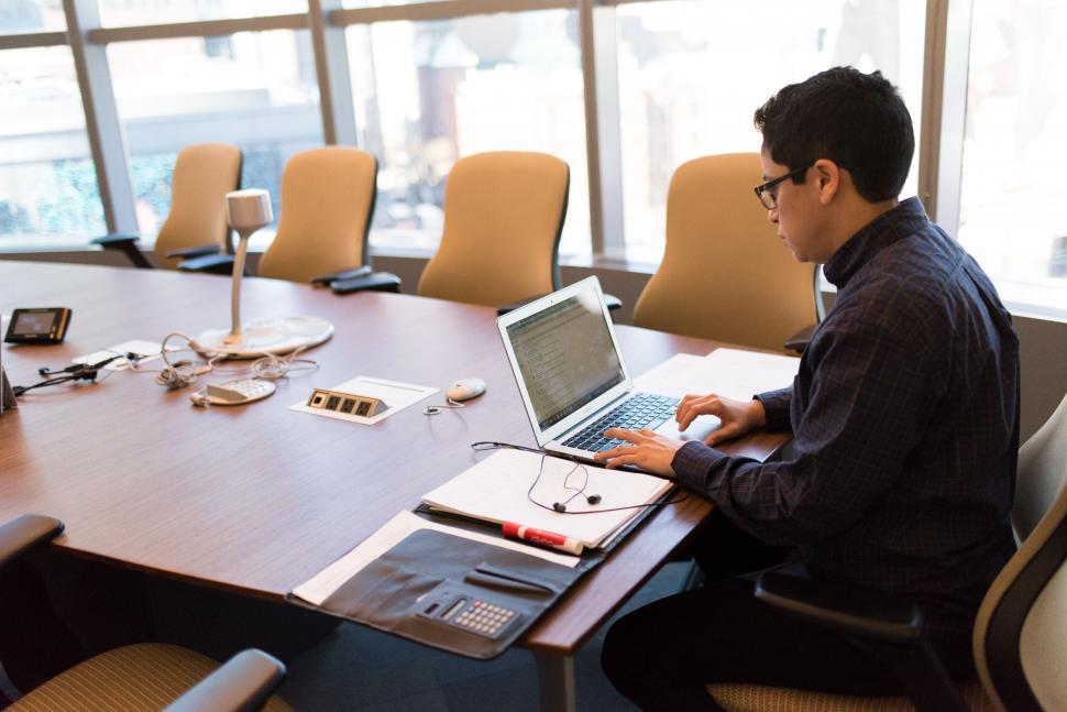 Free Image of Man working alone on laptop at conference table 