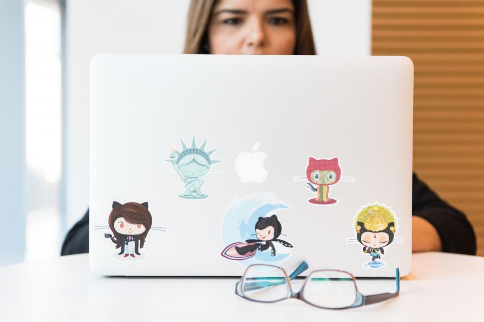 Free Image of Laptop with fun stickers and a peeking teen 
