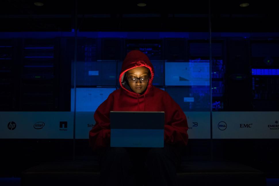 Free Image of Hooded person with laptop in dark server room 
