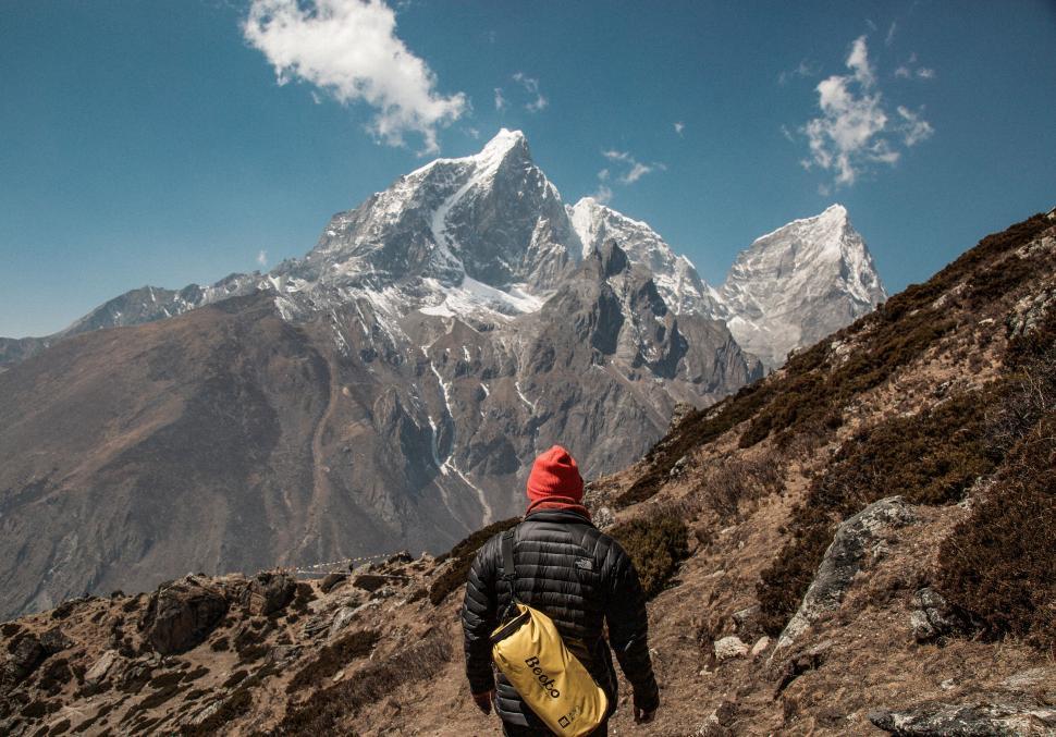 Free Image of Hiker with a yellow backpack walking towards mountains 