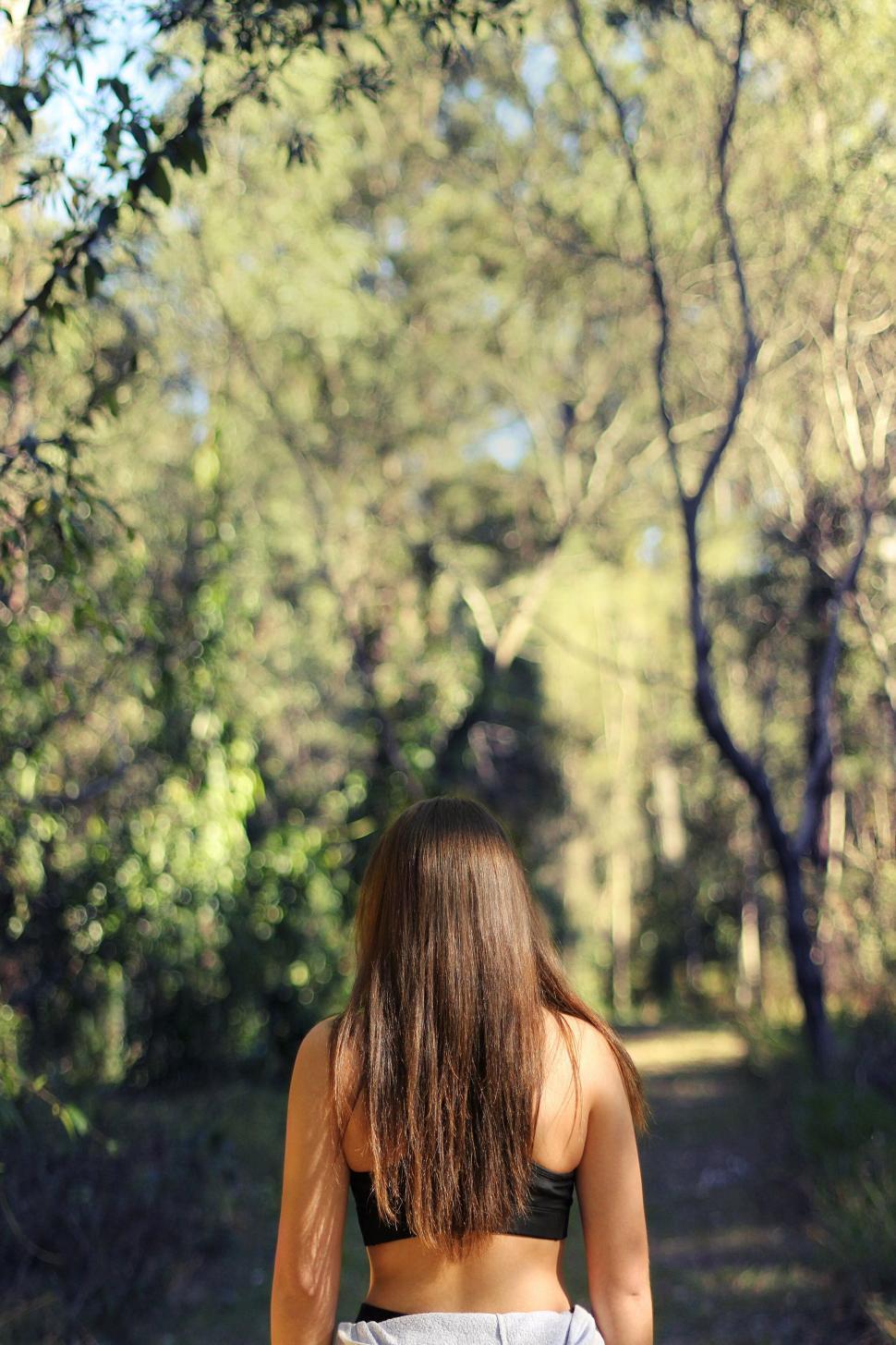 Free Image of Back view of a woman in a forest pathway 