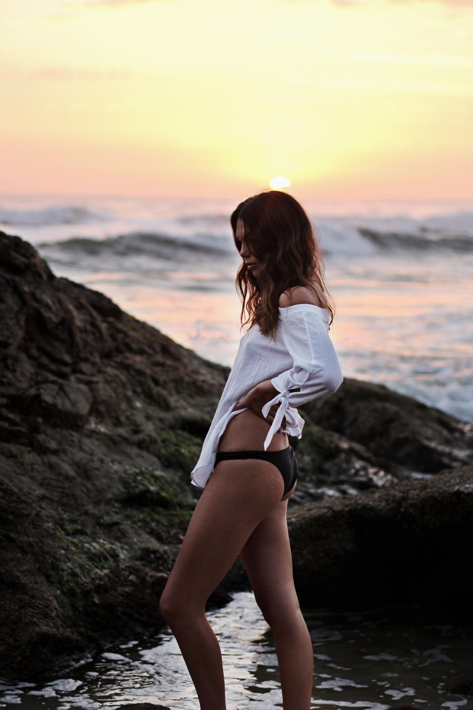 Free Image of Woman in white shirt at beach during sunset 