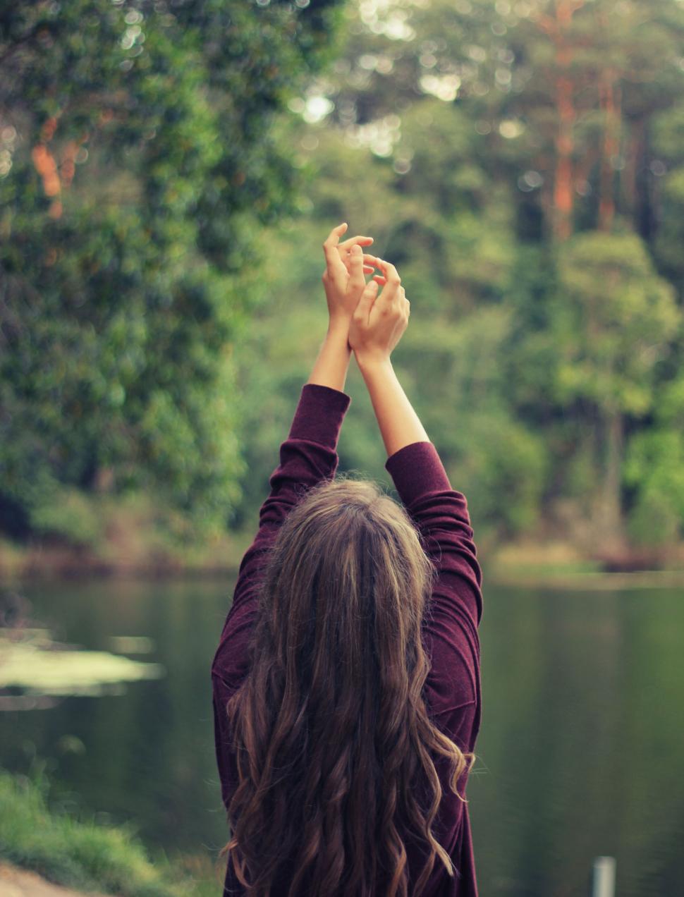 Free Image of Person with raised arms amidst serene nature 