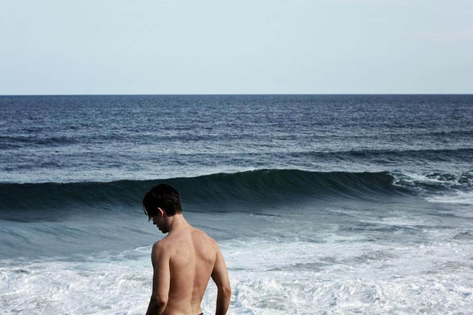 Free Image of Man standing before ocean waves 