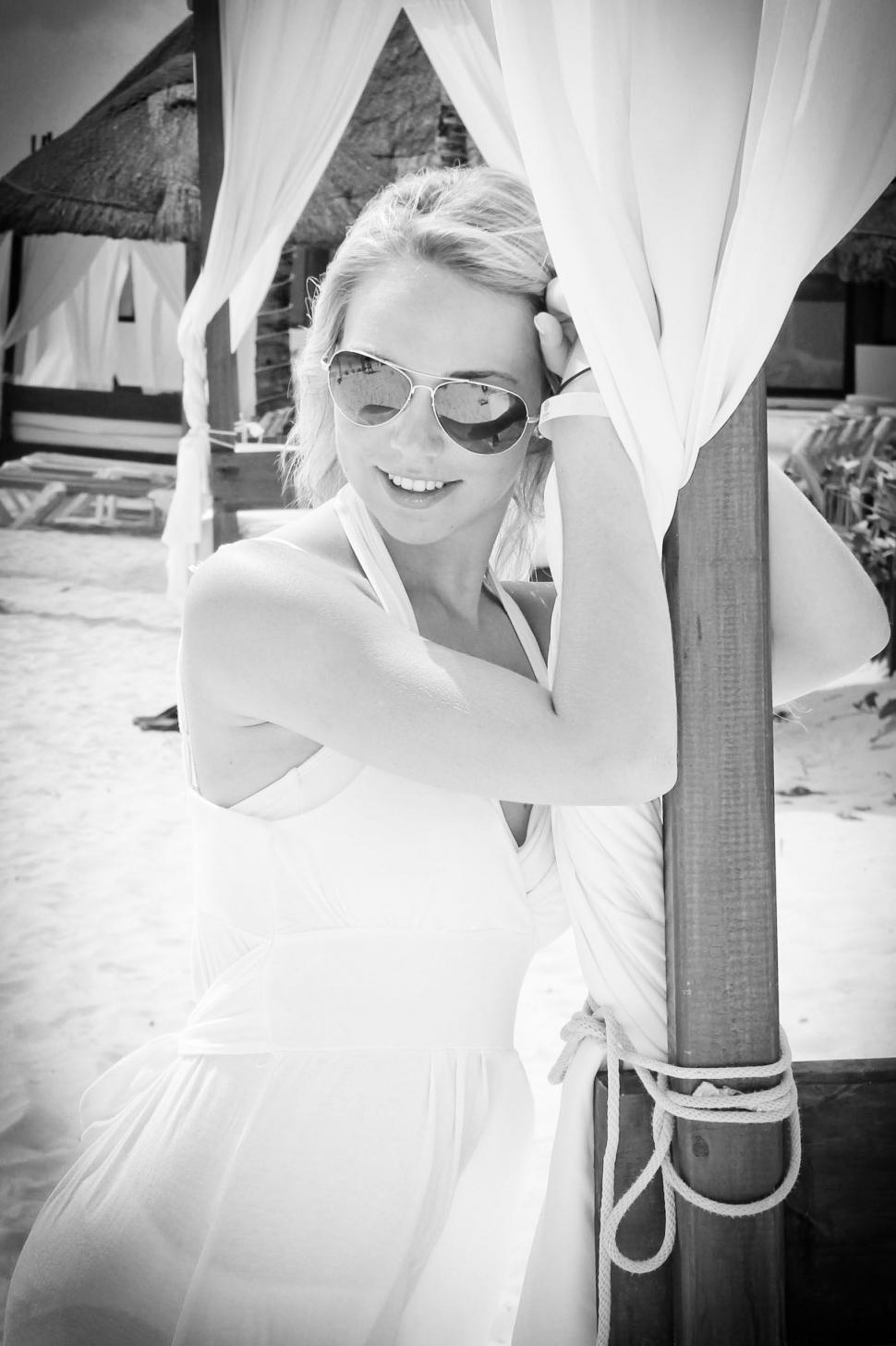 Free Image of Woman in white dress by beach cabana 