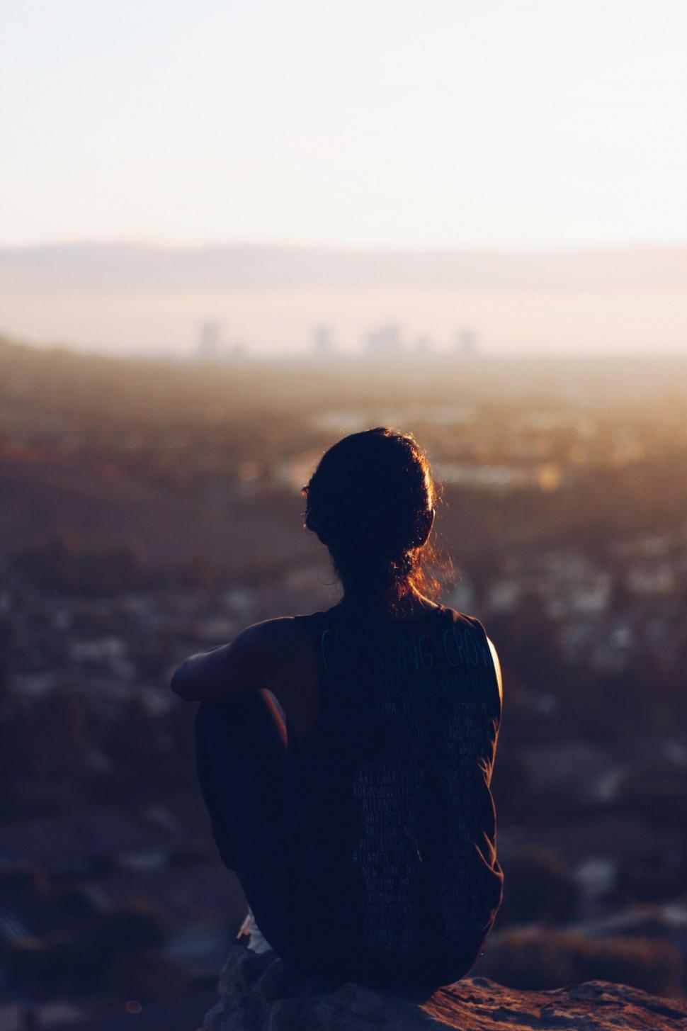 Free Image of Silhouette of woman watching sunset over city 