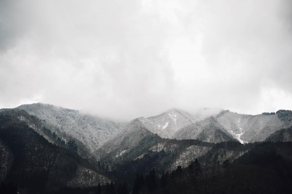 Free Image of Misty snow-covered mountains under cloudy sky 
