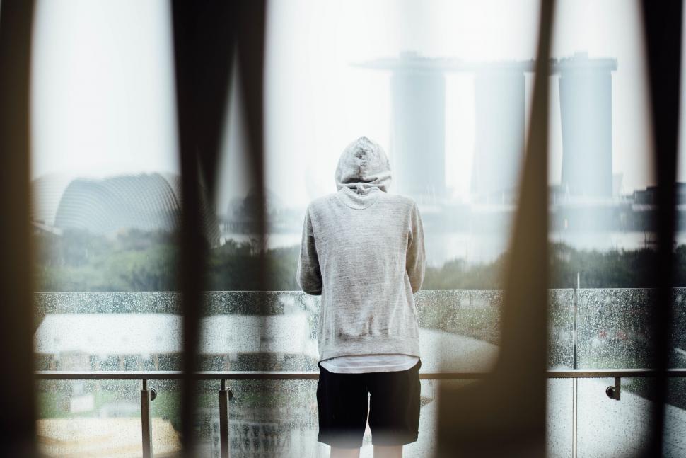 Free Image of Man looking at city through wet glass 