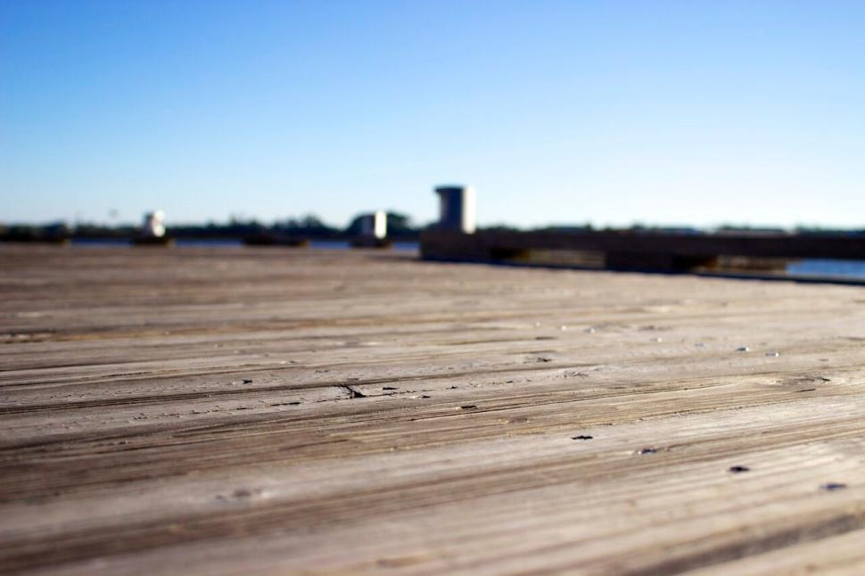 Free Image of Sunlit wooden pier overlooking a serene landscape 