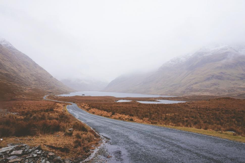 Free Image of Misty road weaving through a rugged landscape 
