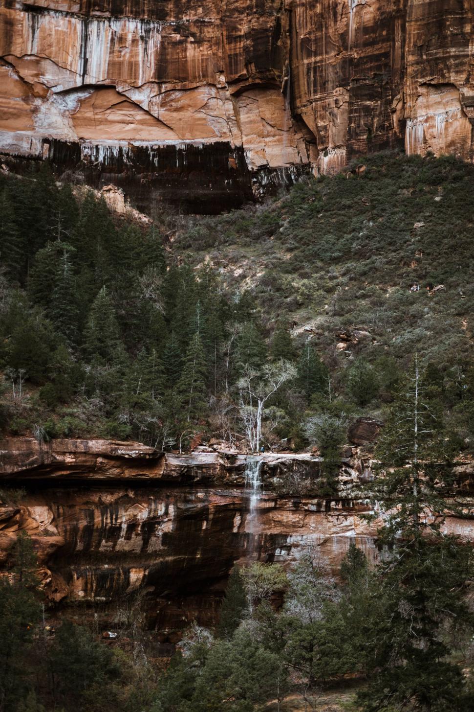 Free Image of Rocky cliffs with a small waterfall and trees 