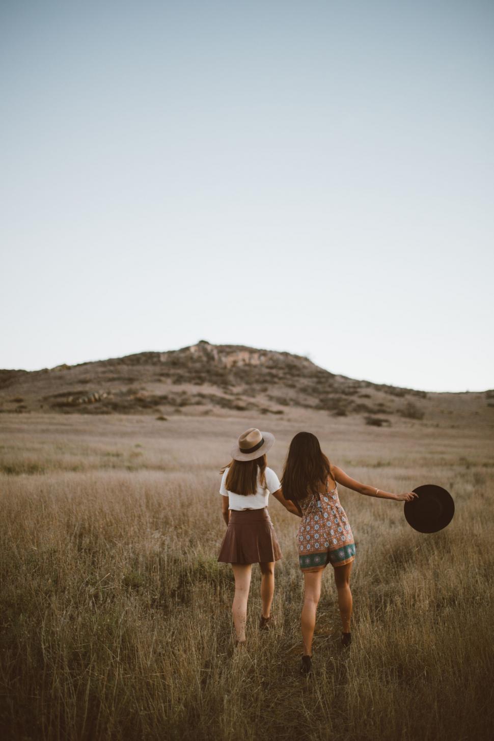 Free Image of Two friends walking hand in hand in a field 