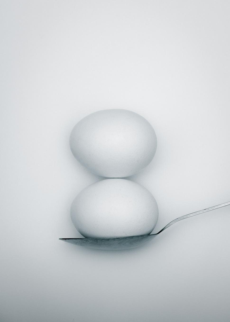 Free Image of Two eggs balanced on a spoon in white space 