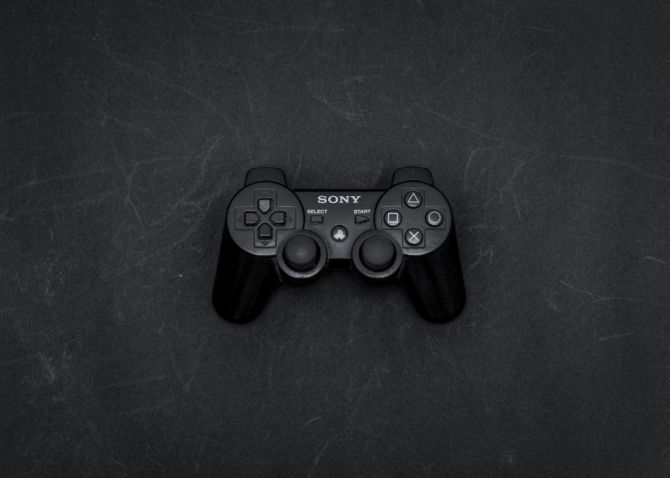 Free Image of PlayStation controller on dark textured surface 