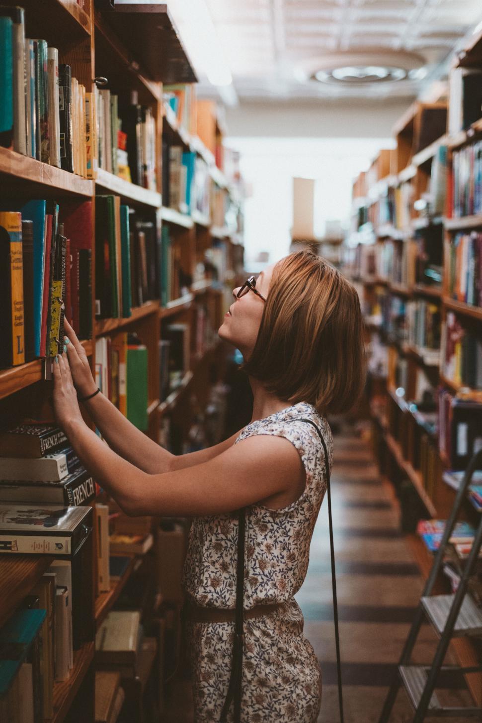 Free Image of Woman browsing books in library aisle 