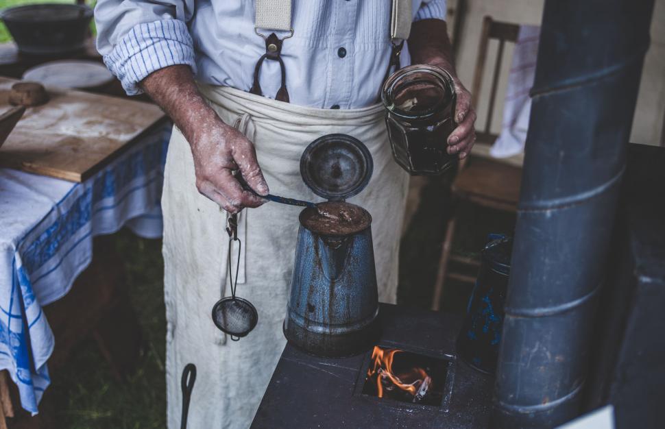 Free Image of Man brewing coffee at a vintage stove 