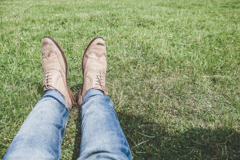 Free Image of Person relaxing on grass with brown shoes 