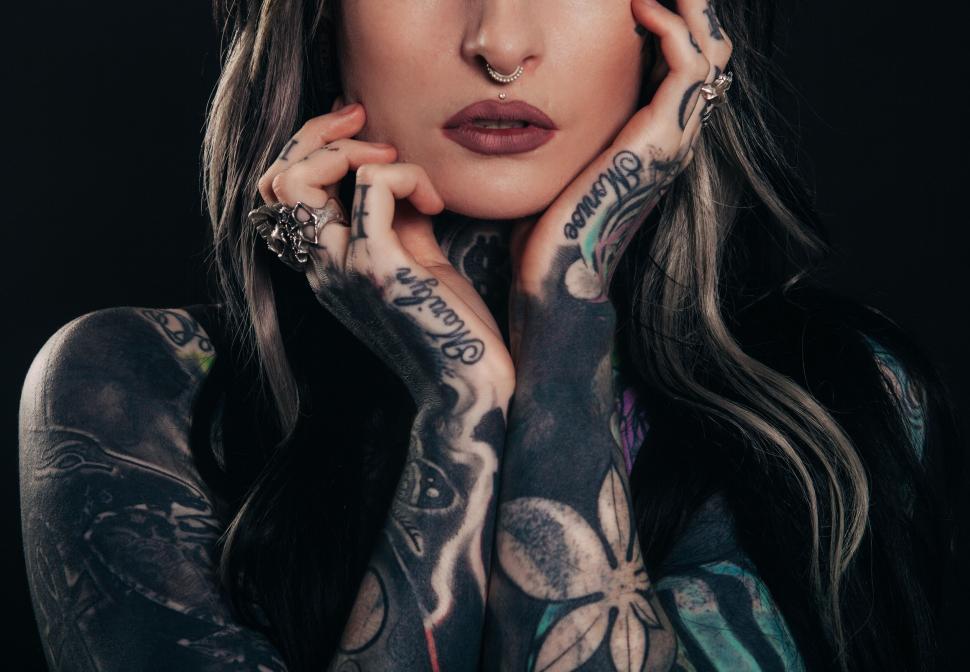 Free Image of Tattooed woman holding her face with hands 