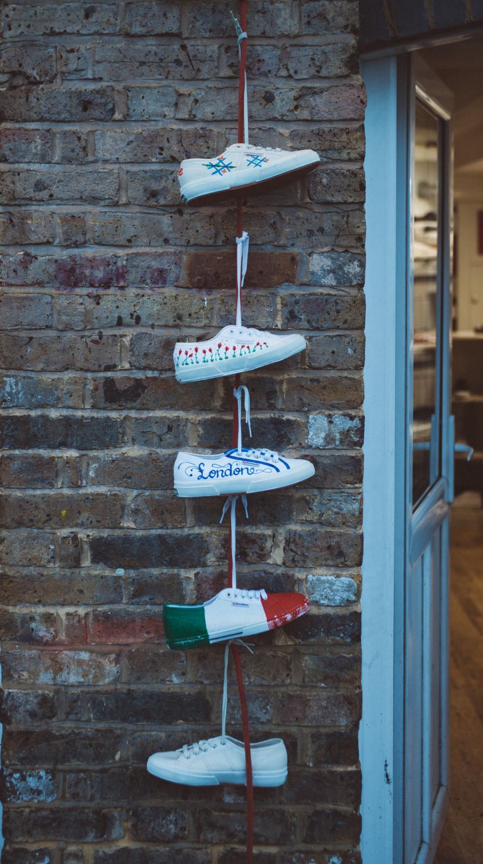 Free Image of Sneakers decorated and hanging on a red rope 