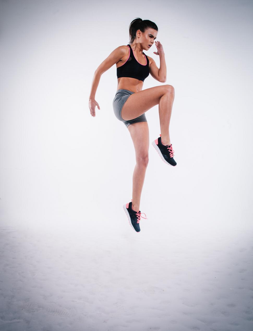 Free Image of Fitness woman mid-jump on white background 