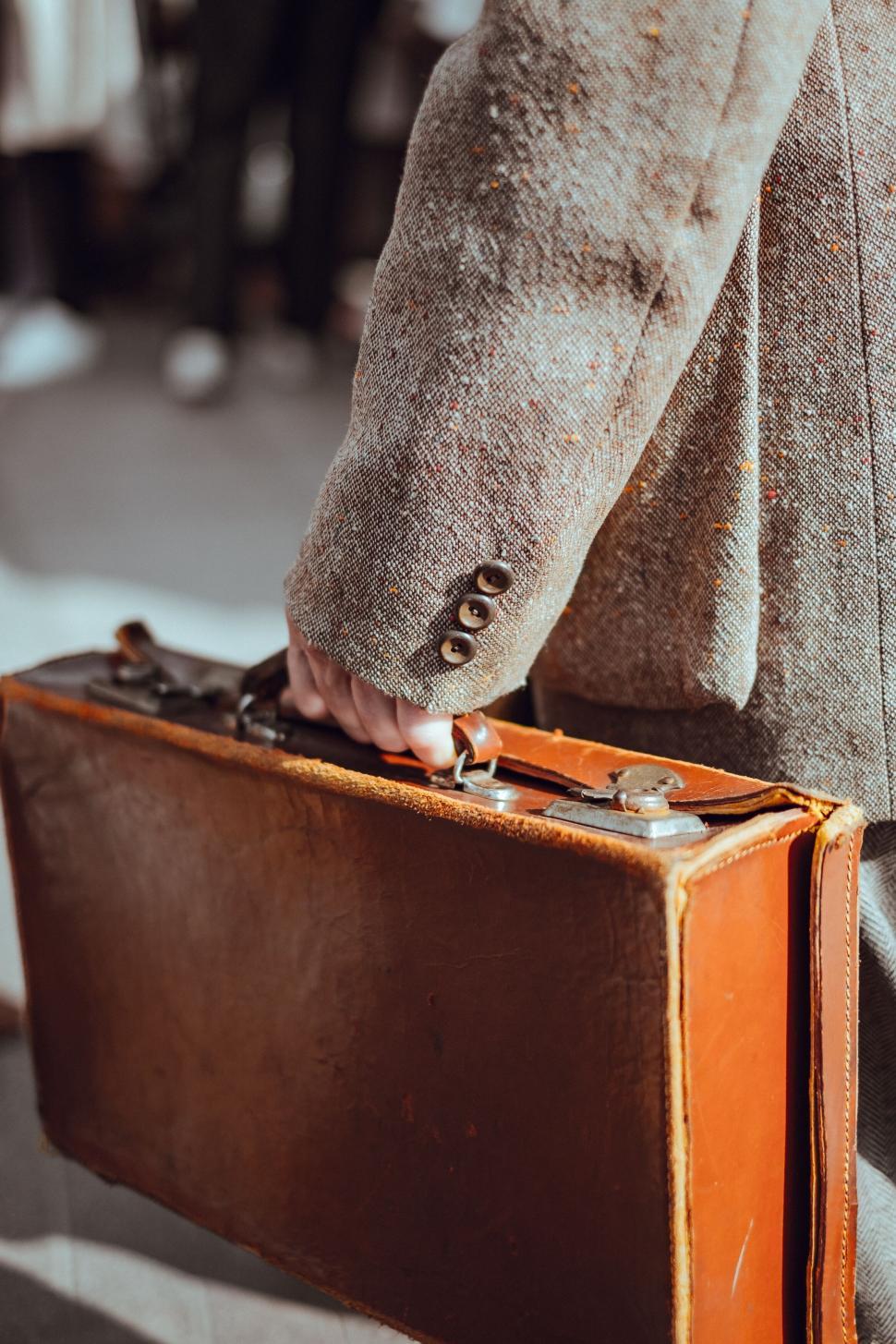 Free Image of Close-up of a hand carrying a vintage briefcase 