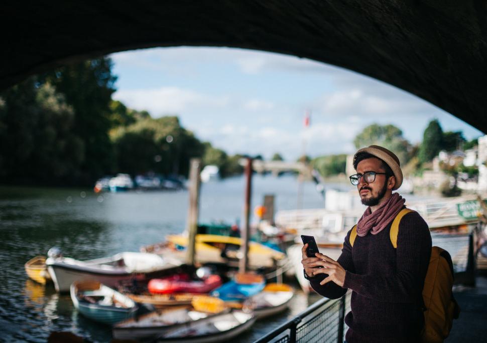 Free Image of Woman by river using smartphone 