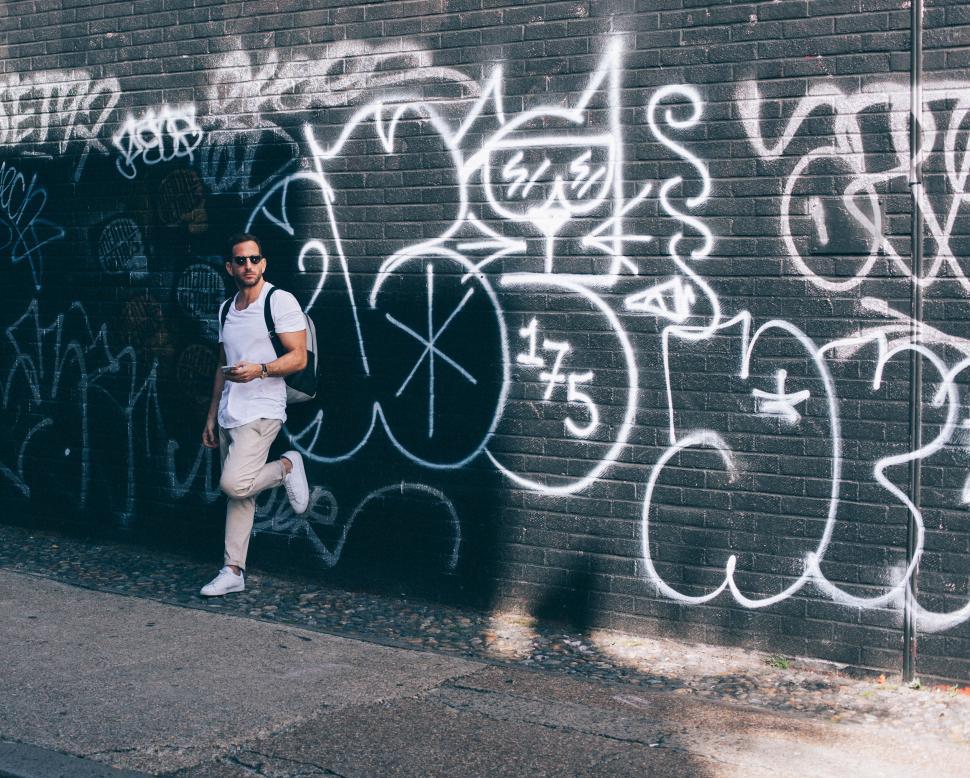 Free Image of Man leaning against wall with graffiti 