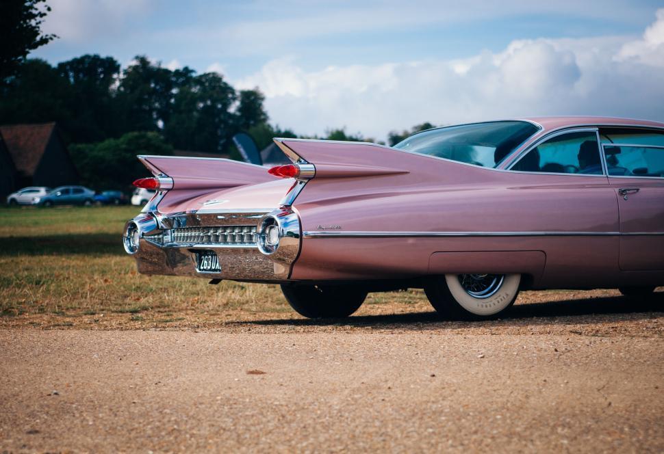 Free Image of Vintage pink Cadillac with tail fins parked 