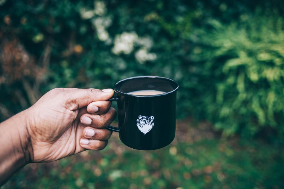 Free Image of Hand holding a black mug with design 
