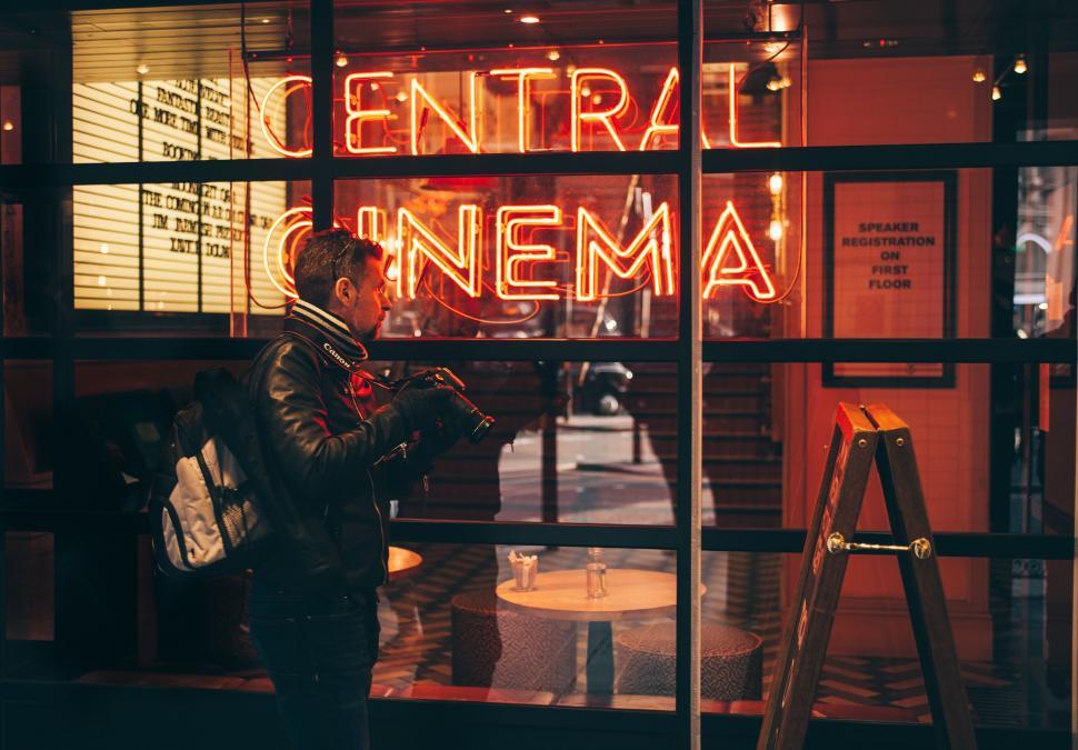Free Image of Person viewing neon  CENTRAL CINEMA  sign 