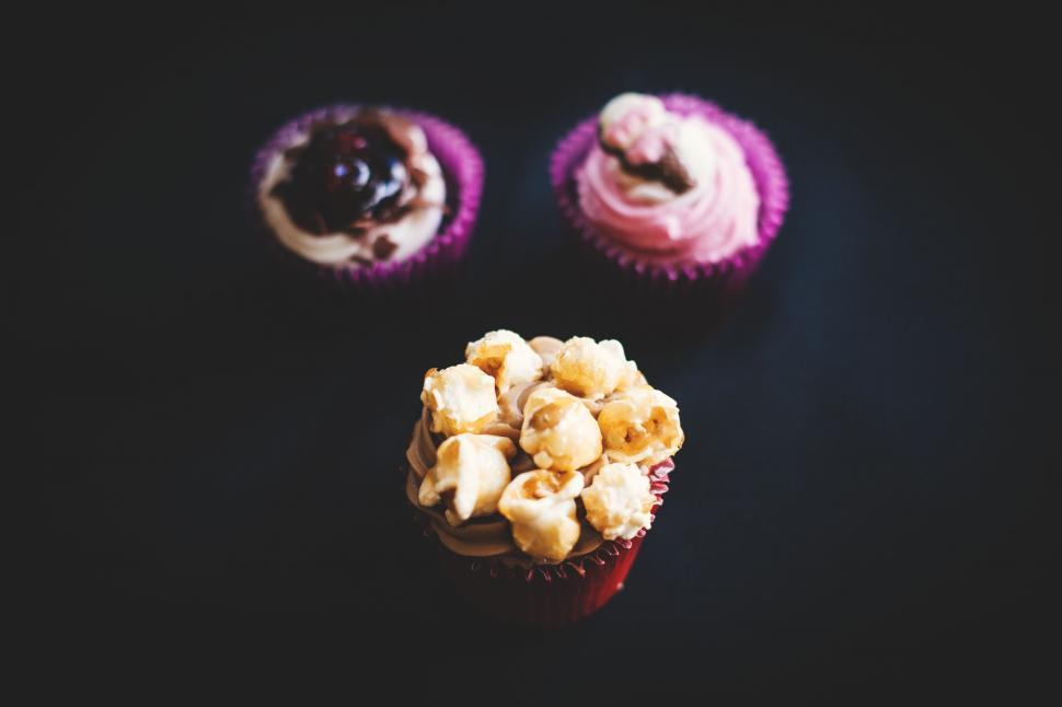 Free Image of Three cupcakes with various toppings on dark background 