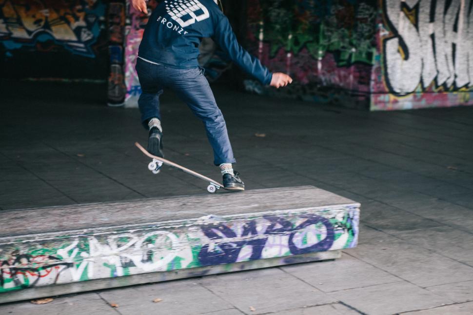 Free Image of Skateboarder performing trick on graffiti ledge 