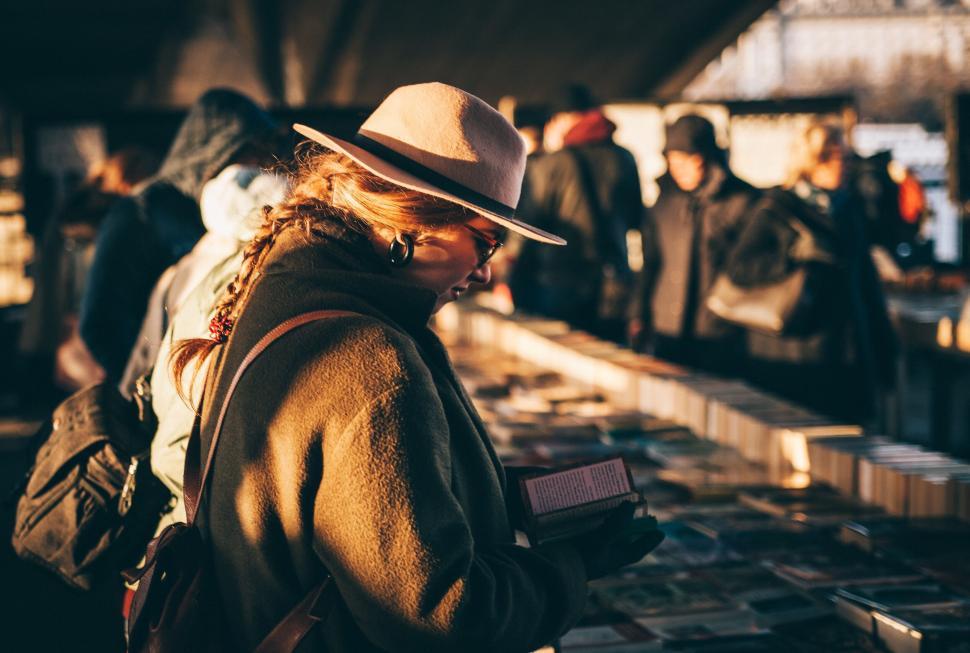 Free Image of Woman browsing books at outdoor market 