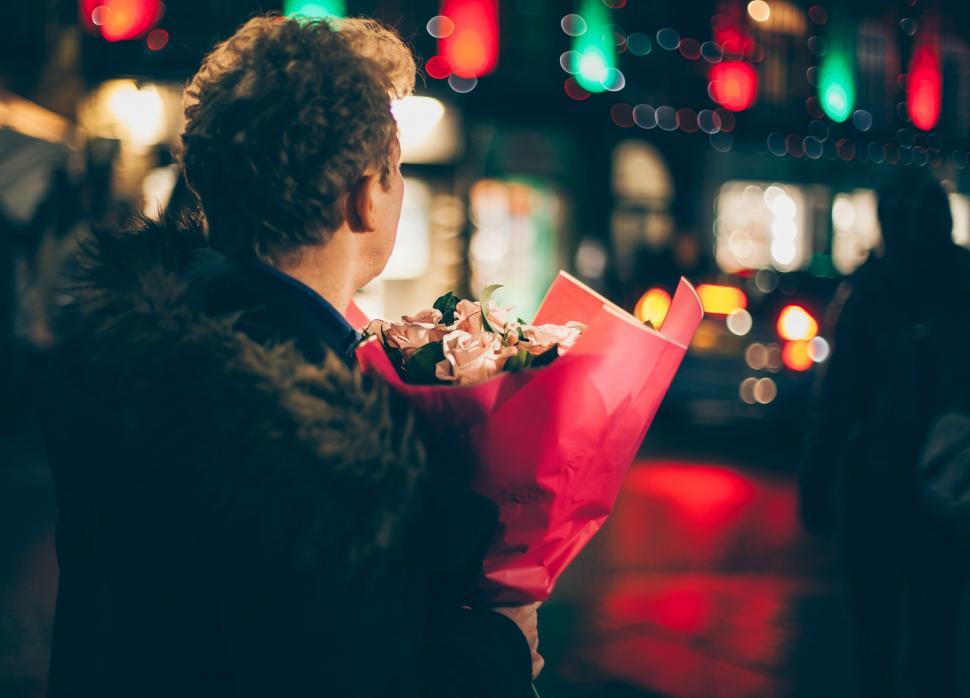 Free Image of Man holding flowers on a city night 