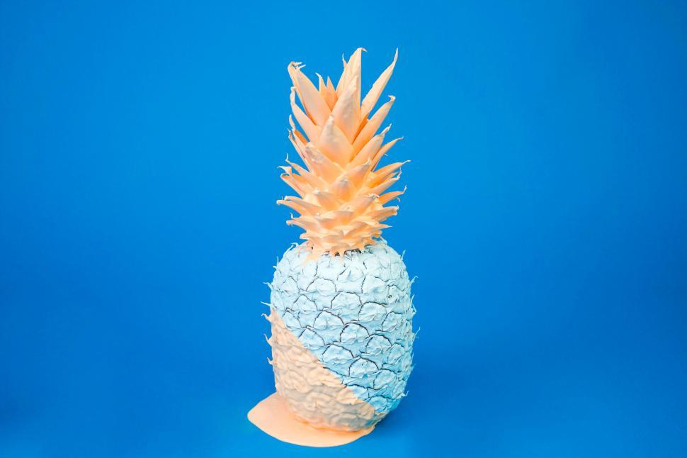 Free Image of Painted pineapple with a colorful top on blue 