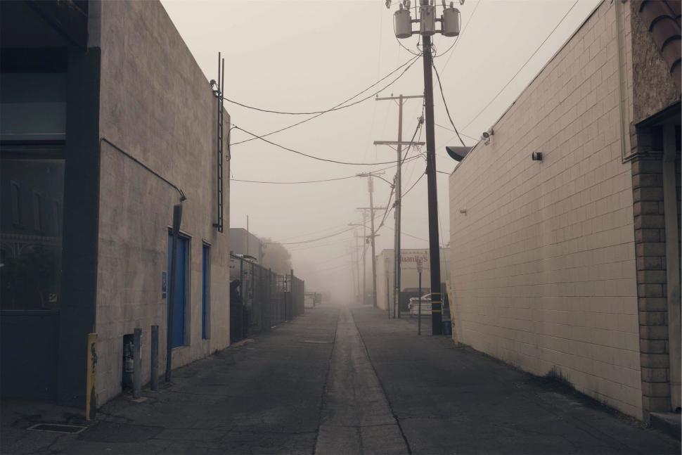 Free Image of Foggy urban alley with buildings and power lines 