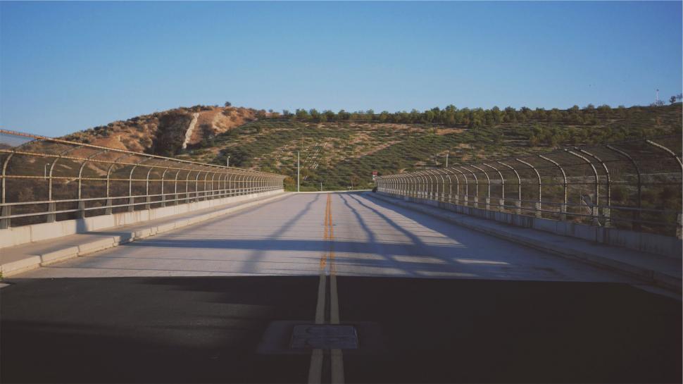 Free Image of Serene bridge leading to a hill with railings 