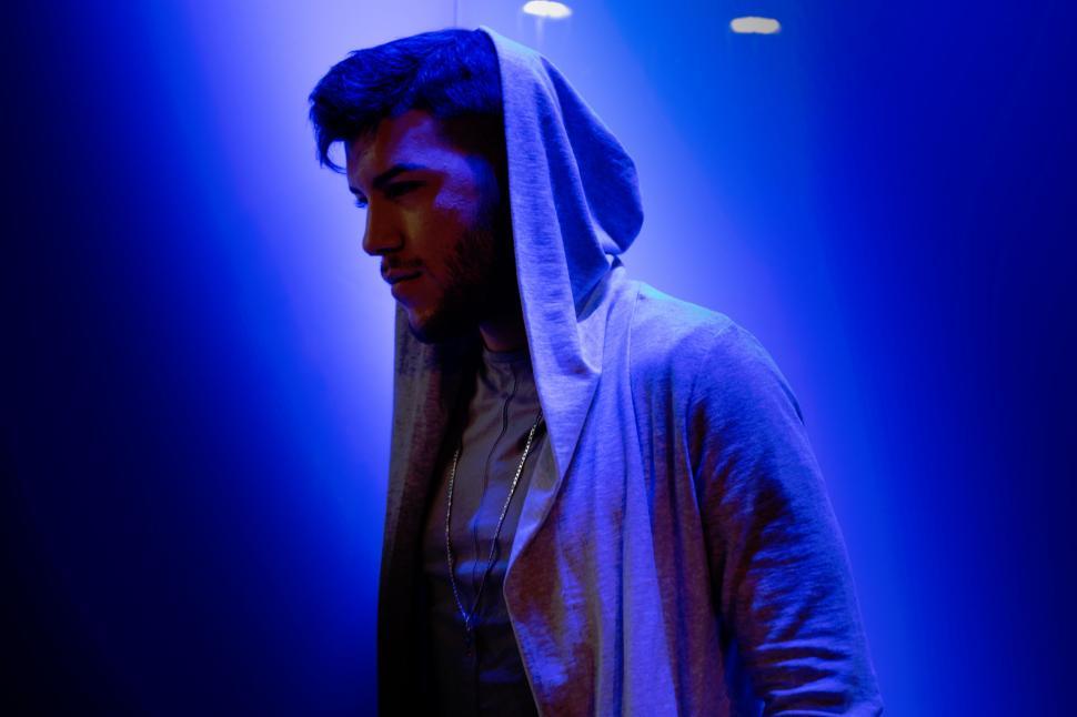 Free Image of Mysterious figure in a hoodie under blue light 