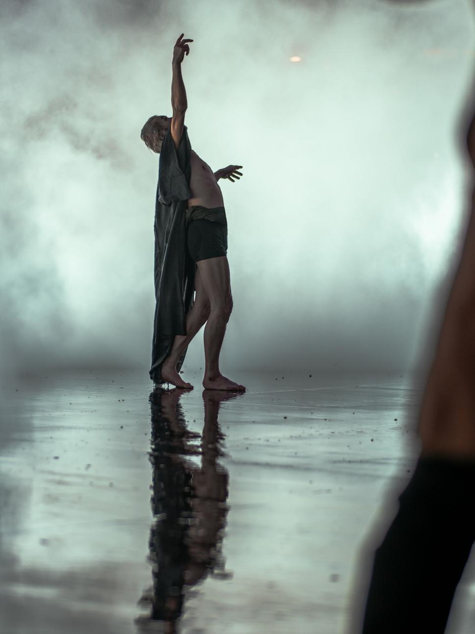 Free Image of Dancer s reflection on water in smoky room 