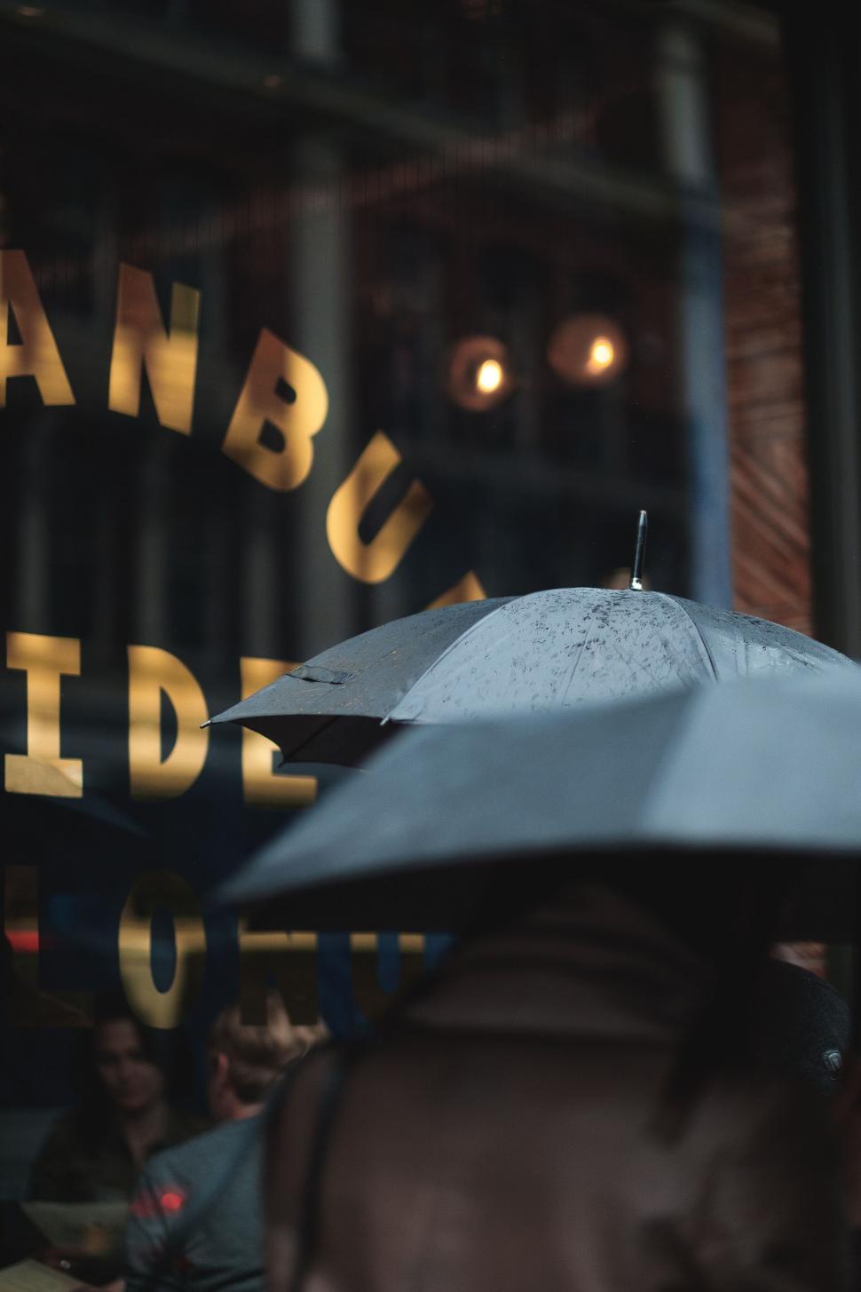 Free Image of Person with umbrella by a shop window 