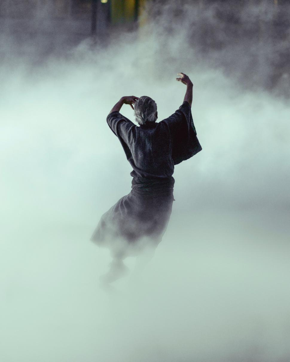 Free Image of Figure wrapped in cloak dancing in mist 