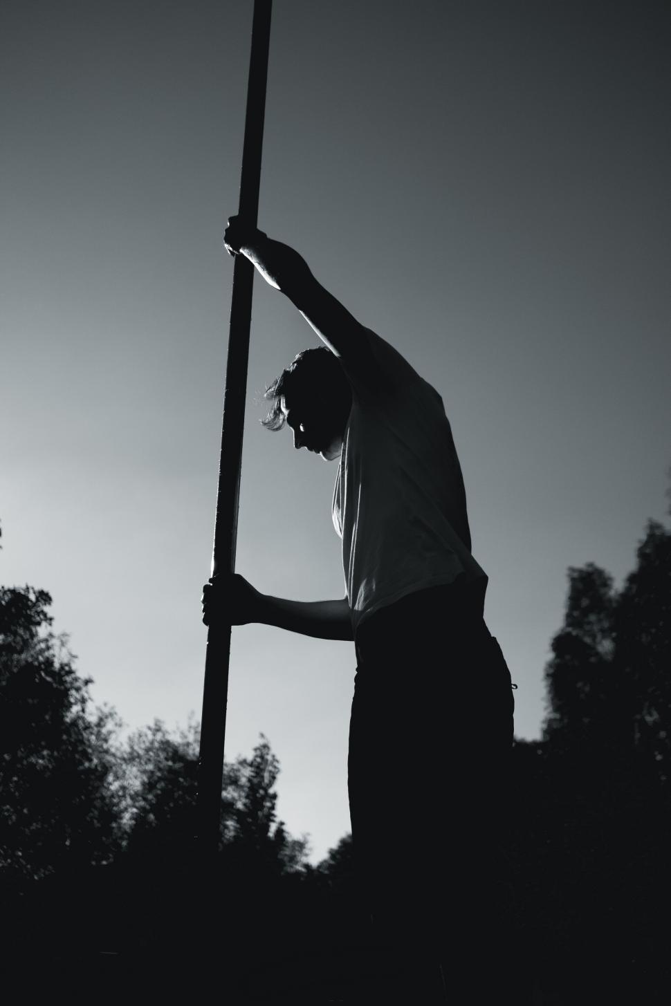 Free Image of Man leaning on pole in silhouette against sky 