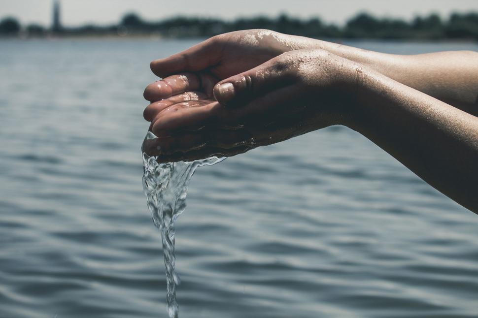 Free Image of Hand scooping clean water from tranquil lake 