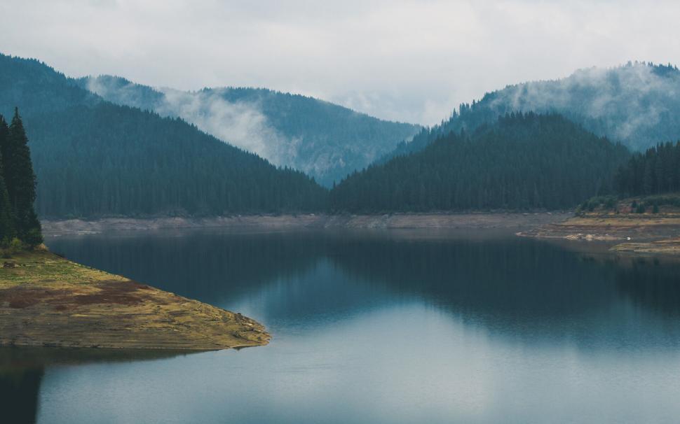 Free Image of Misty lake surrounded by forested hills 