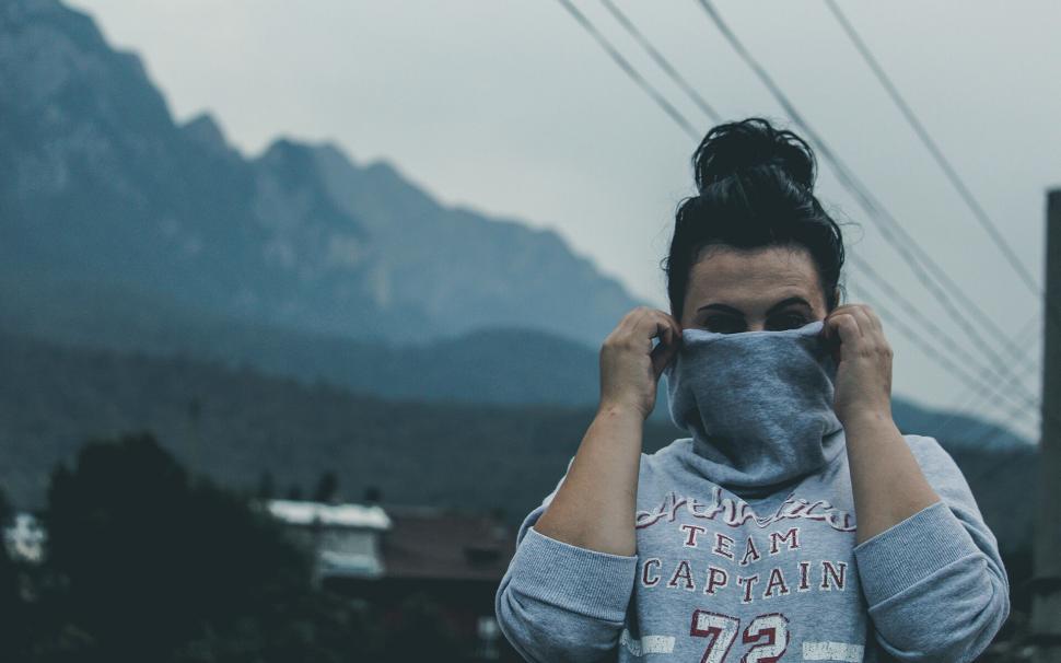 Free Image of Person adjusting a face mask in a mountainous area 