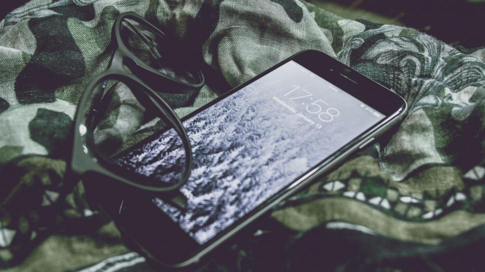 Free Image of Smartphone and glasses on camo fabric 