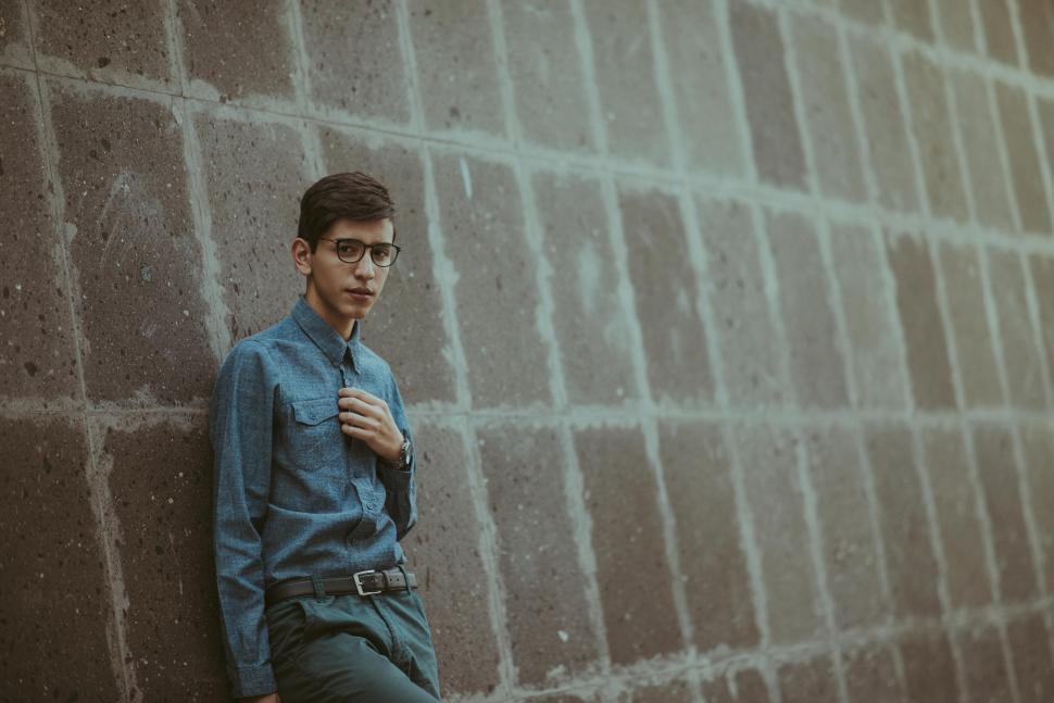 Free Image of Young man leaning against concrete wall 