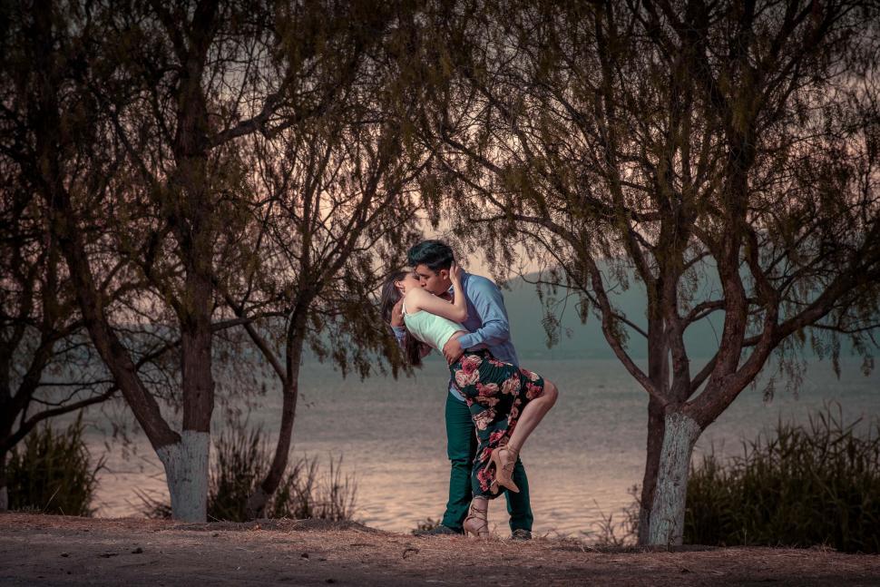 Free Image of Couple with blurred faces dancing under trees 
