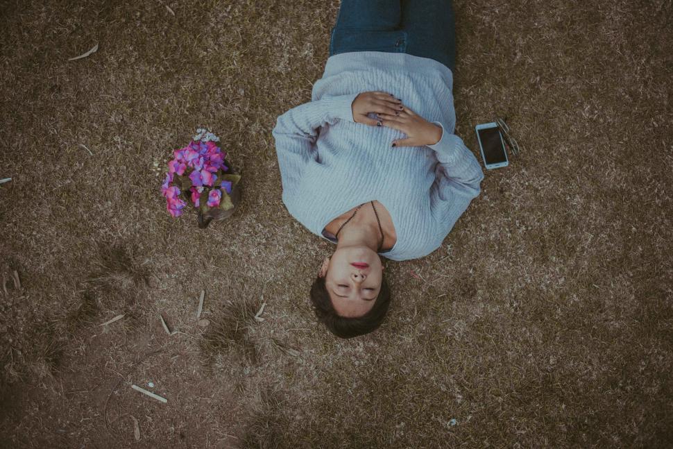 Free Image of Person lying on grass with a bouquet 